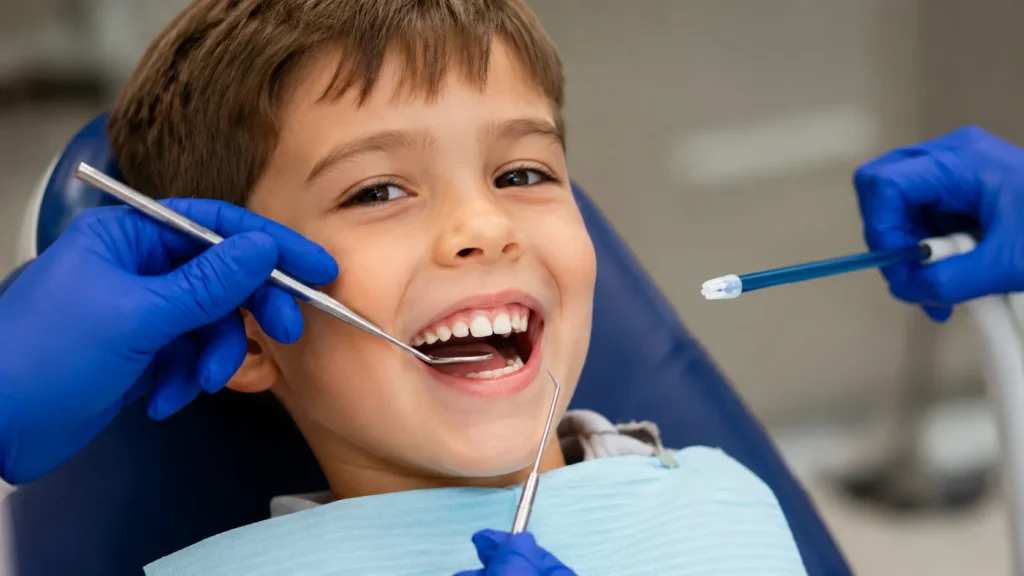 Bambino sorridente sulla poltrona del dentista pediatrico durante una visita di controllo
